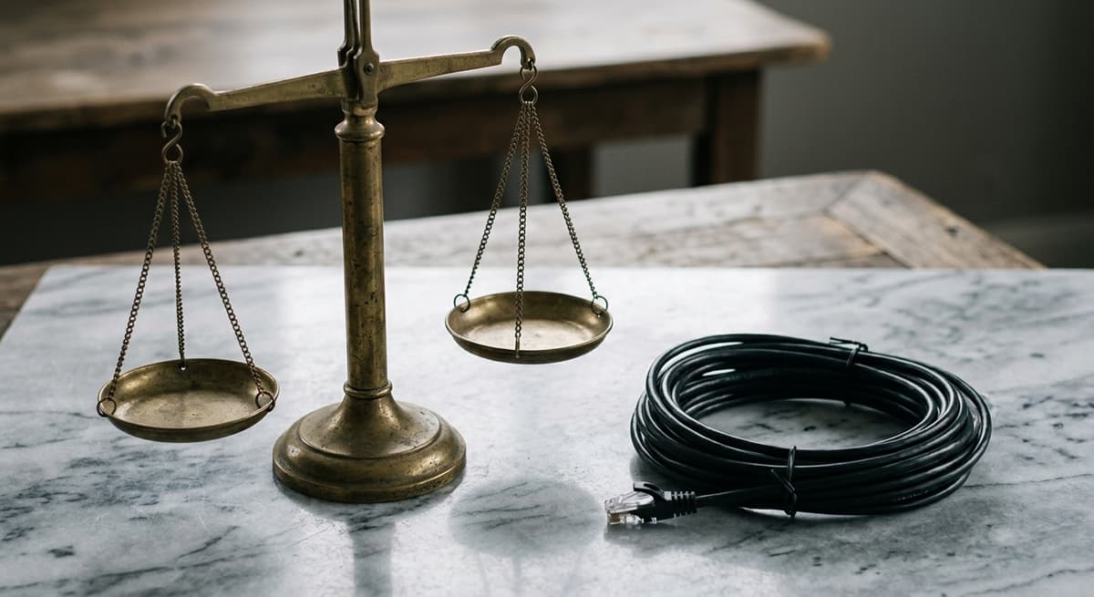 brass scale of justice beside coiled network cable