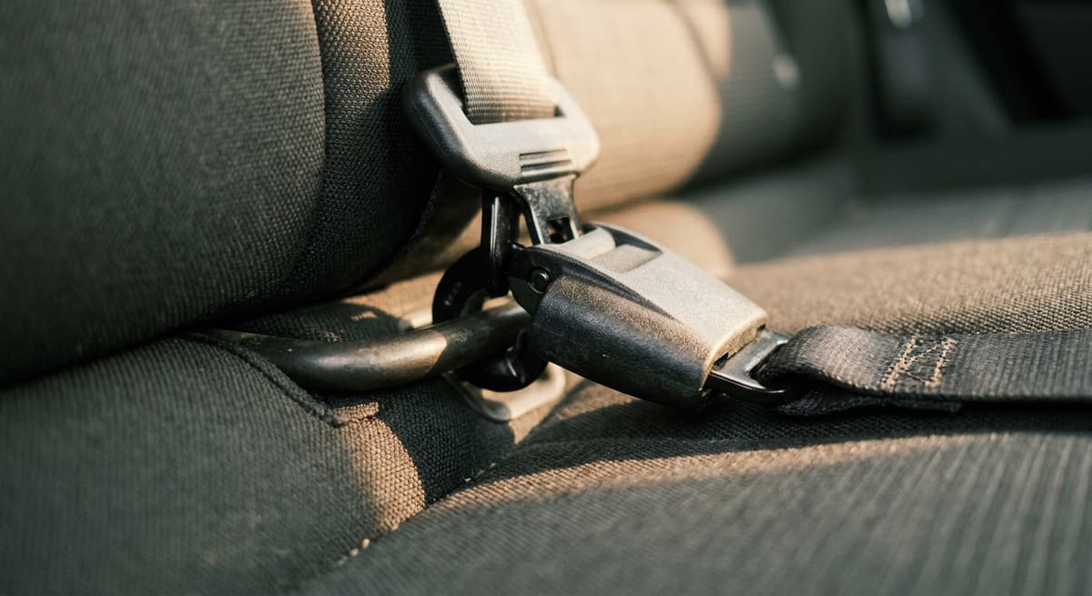 a LATCH lower-anchor connector hooked onto the metal anchor bar in a back seat