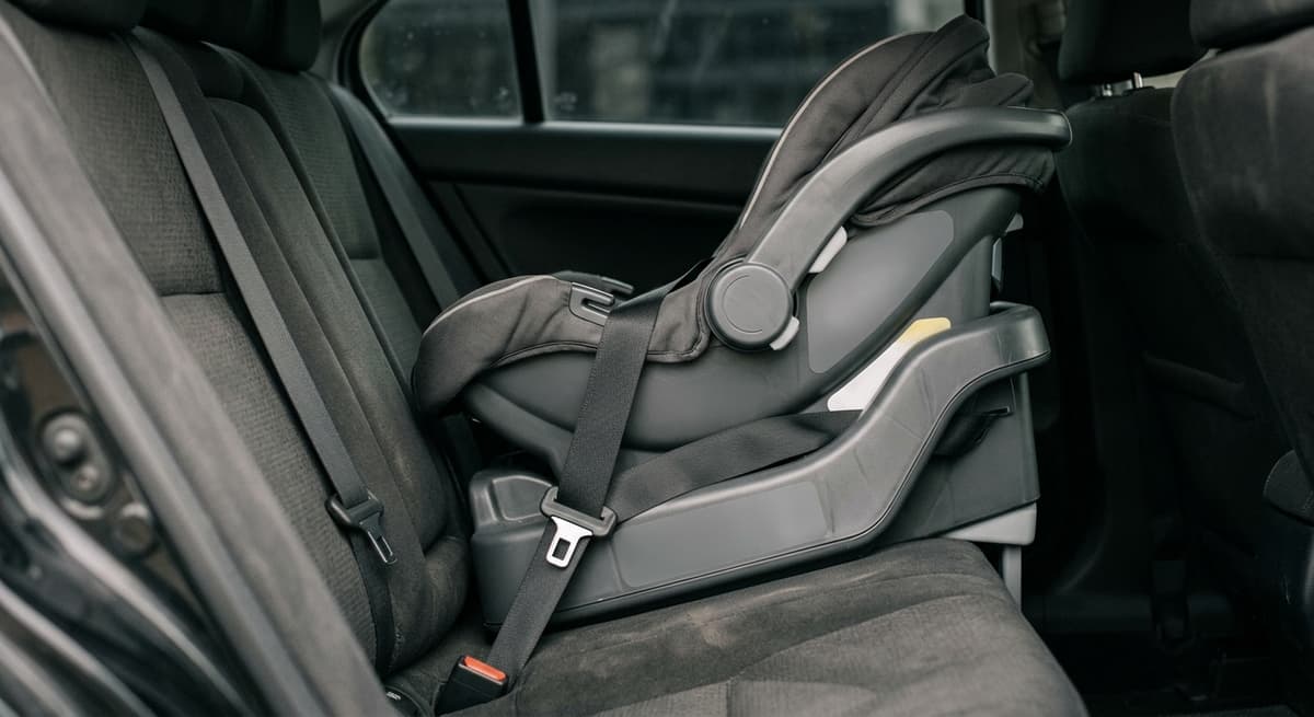 a rear-facing infant car seat base secured with a seatbelt in a vehicle back seat