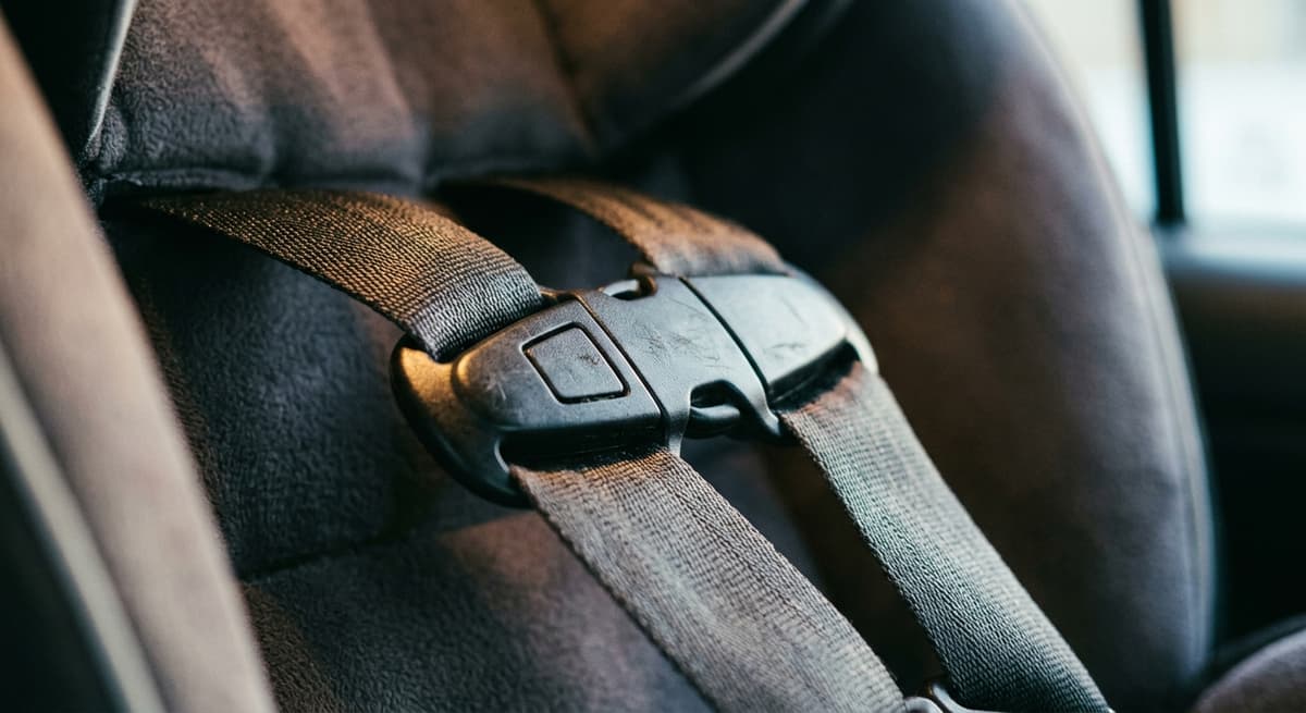 Un broche de pecho abrochado en el arnés de un asiento de seguridad para niños, primer plano