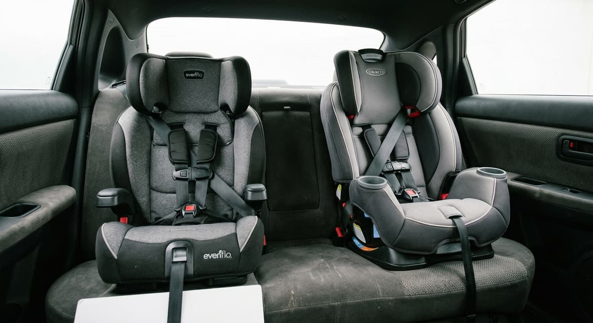 two child car seats installed side by side across a vehicle back bench