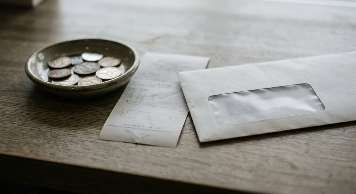 a small coin tray and printed receipt on a service counter beside a document window envelope