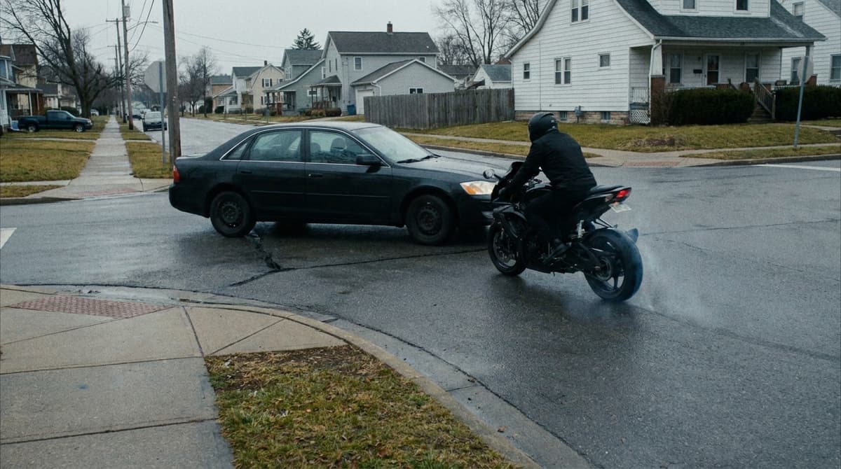 Sedan turning left across an intersection directly in front of an oncoming motorcycle that is braking and sliding