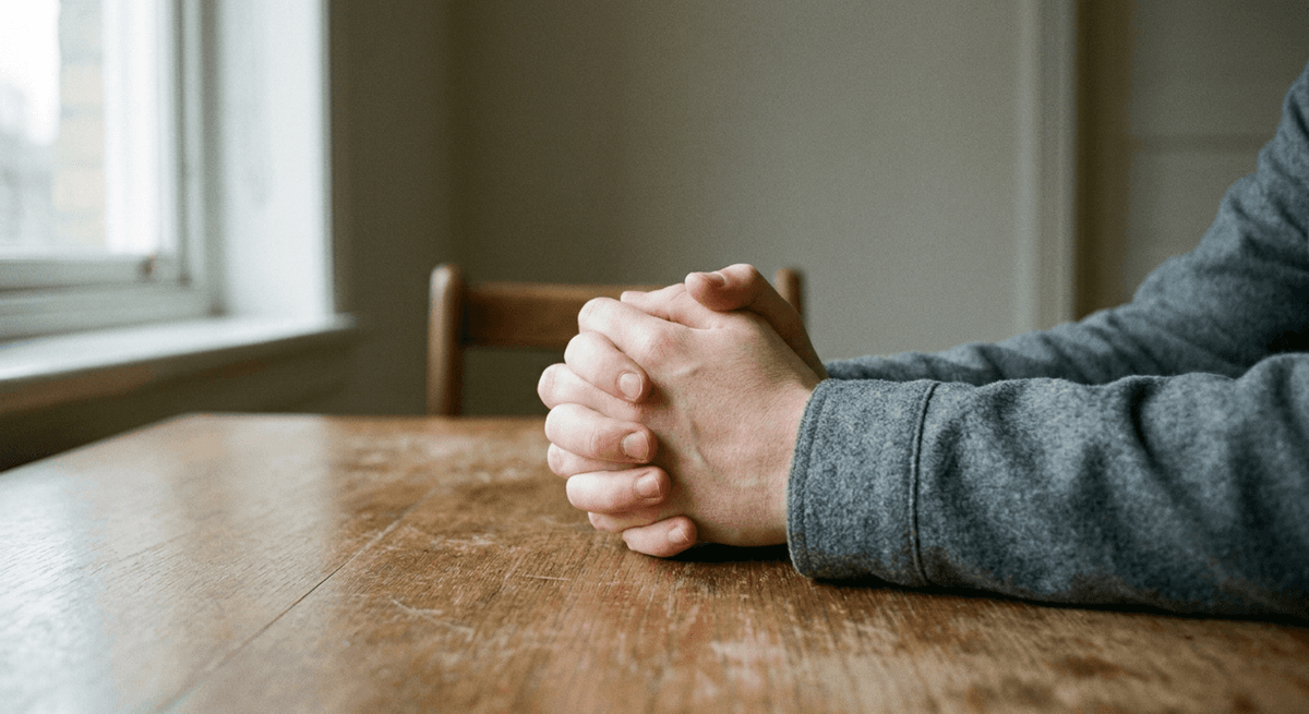 Dos manos entrelazadas sobre una mesa de madera con luz suave de ventana
