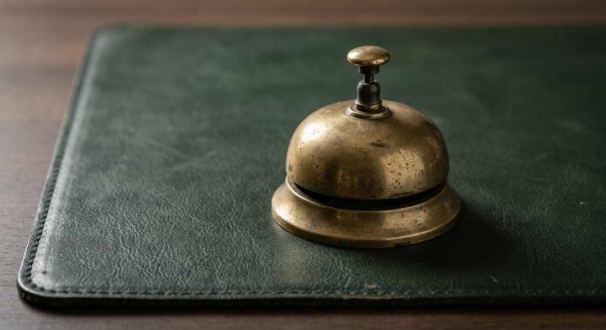 World vintage brass desk bell on a dark green leather desk mat