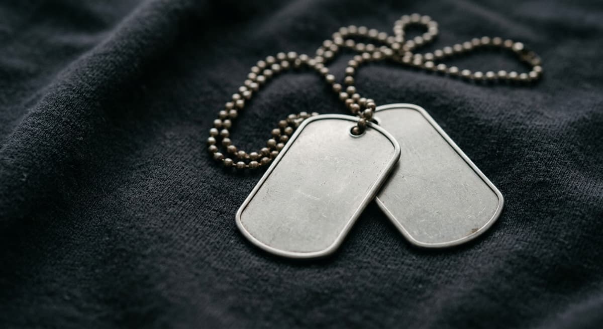 a close-up of metal dog tags with blank faces resting on dark fabric