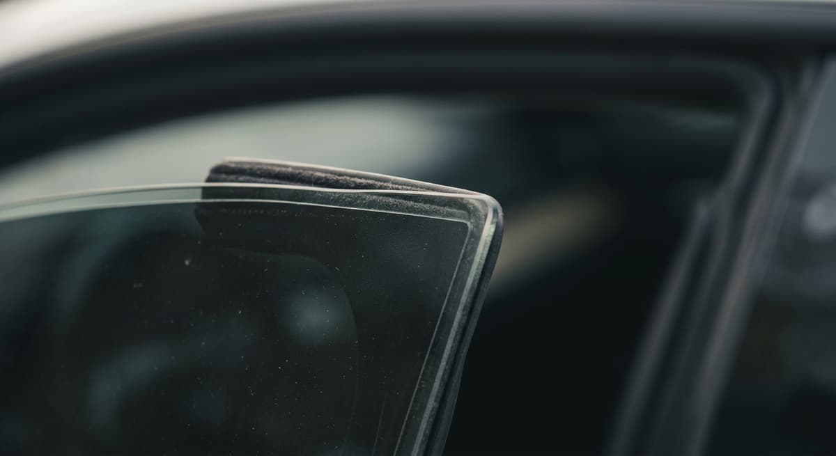 a close-up of a car side window with a clean tint film edge, no people
