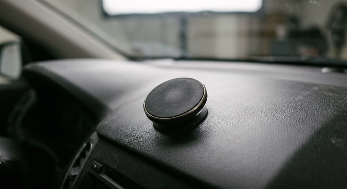 A round magnetic phone-mount disc stuck to a matte dashboard